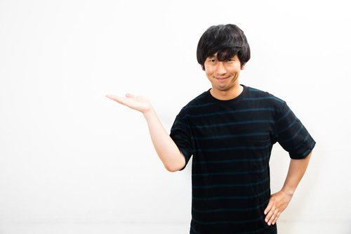 黒いTシャツの男性による怪しい薄ら笑いの案内ポーズ