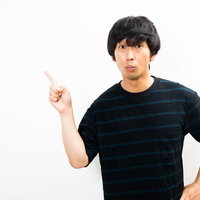 指を上向きに差して説明するボーダーTシャツの男性の写真