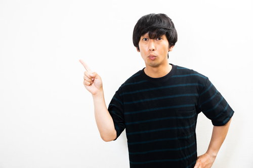 指を上向きに差して説明するボーダーTシャツの男性