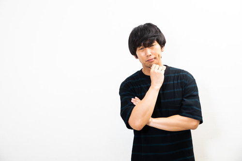 しかめっ面して悩む男性（白背景）
