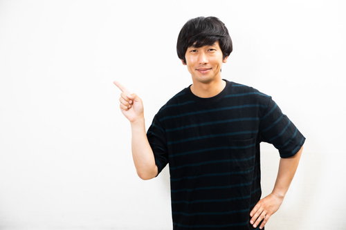 笑みを浮かべながら右手で指差し説明する男性
