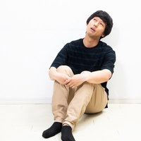 膝を抱えてボーっとする男性の写真