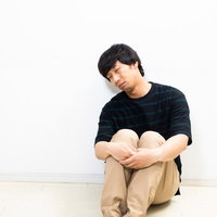 膝を抱えて不貞腐れる男性の疲労感と心身の疲弊の写真