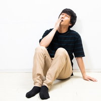 隅に追いやられ後悔する、膝を抱えて落ち込む男性の写真