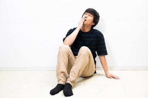 隅に追いやられ後悔する、膝を抱えて落ち込む男性