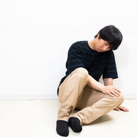 膝を抱えて座り込んでうずくまる男性のストレス・疲労の写真