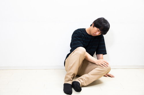 膝を抱えて座り込んでうずくまる男性のストレス・疲労