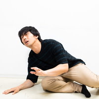 ぎっくり腰で床に座り込む落ち込む男性の写真