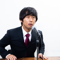 えー、その件については事実確認中です。記者会見で釈明する男性の写真