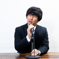 黒いスーツの男性が頭を下げる記者会見での謝罪の写真