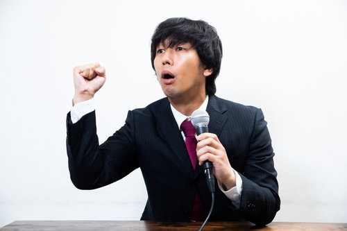 マイクを使って力説する男性のビジネススピーチシーン