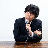 コメントを求められて渋々答える評論家の男性の写真