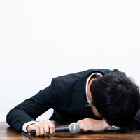 会見中にマイクの前で号泣してしまう広報男性の写真