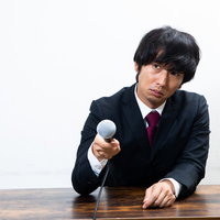 マイクを向けられて困惑する男性への直取材の写真