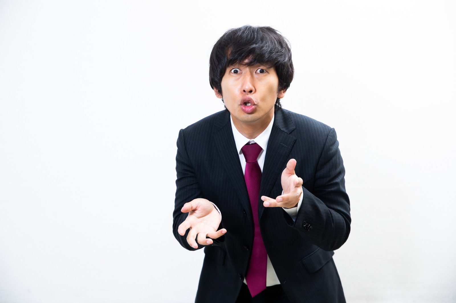 スーツを着た男性が両手を広げてジェスチャーをしながら説明している［モデル：大川竜弥］