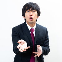 黒いスーツで前のめりに力説する男性の演説シーンの写真