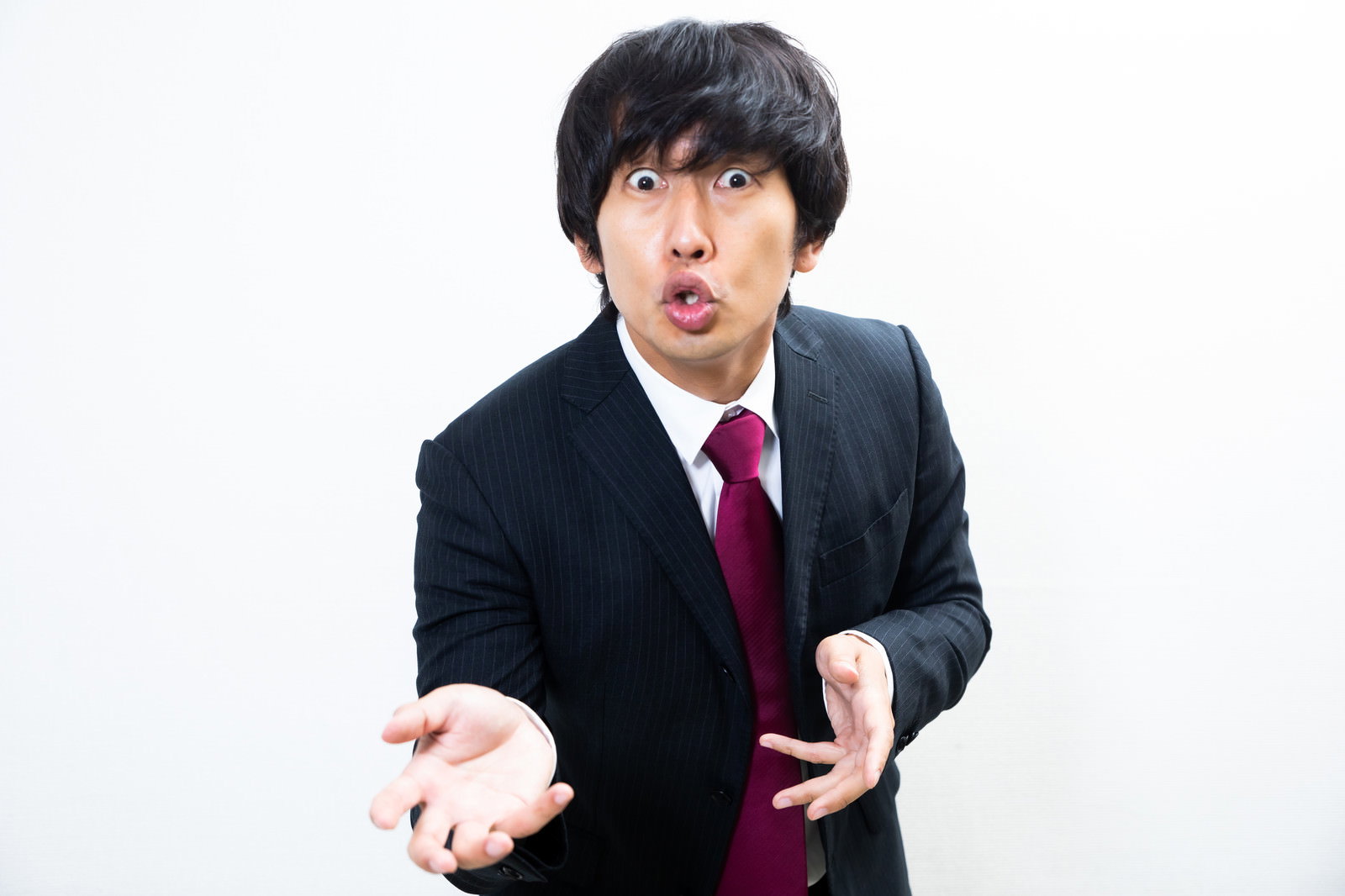 スーツを着た男性がひょっとこのような口の形で力説している様子［モデル：大川竜弥］