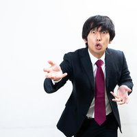 スーツ姿で右手を上げて力説する講師の演説シーンの写真