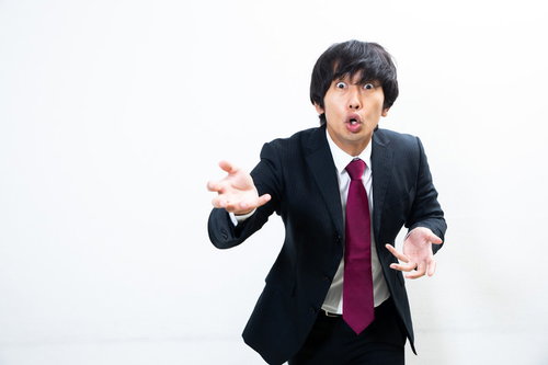 スーツ姿で右手を上げて力説する講師の演説シーン