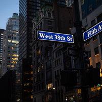 ニューヨークの街角に建ち並ぶビルとストリートサインの写真