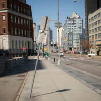 ニューヨークの街角で折れた標識と歩道の道路景観の写真