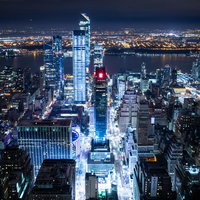 ニューヨークの夜景に浮かび上がるエンパイアステートビルと高層ビル群の写真