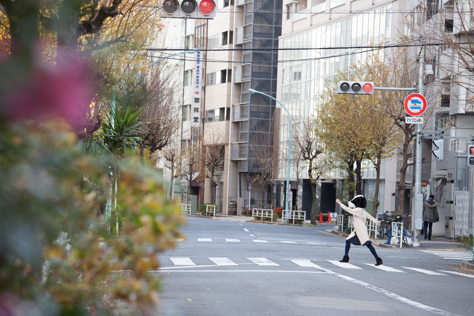 白いベストを着たエト牛のかぶりものの女性が横断歩道を歩いている［モデル：古性のっち］