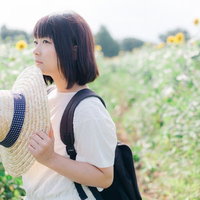 ひまわり畑で麦わら帽を持つ黒髪ショートヘアの夏の女性の写真