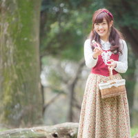 森でバスケットを持ち笑顔で小瓶を売る少女の写真