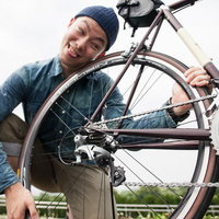 自転車のタイヤとホイールをメンテナンスする男性の写真