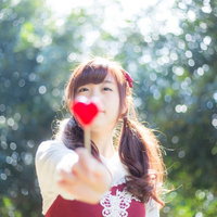 これあげるっ！赤いハートのキャンディを差し出す女性の写真