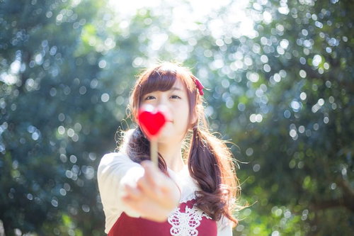 これあげるっ！赤いハートのキャンディを差し出す女性