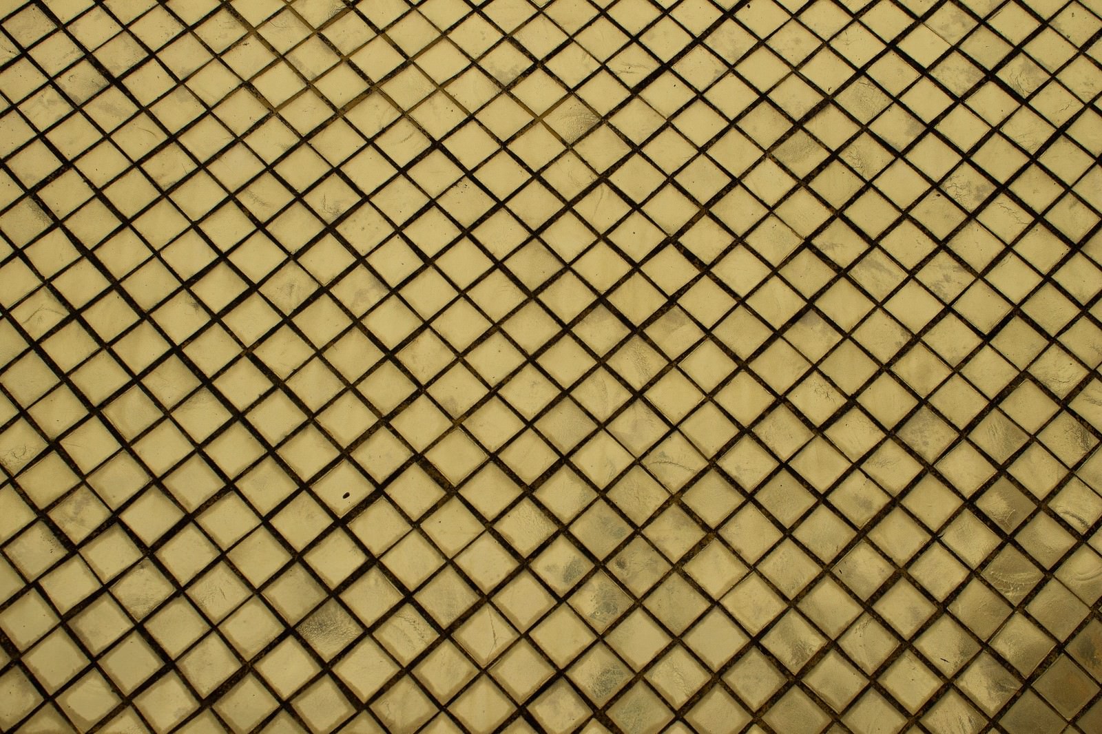 黒い斜め格子模様が並ぶ黄色いタイル表面のテクスチャー