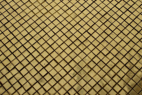 黒い斜め格子模様が並ぶ黄色いタイル表面のテクスチャー