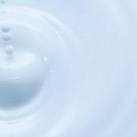 飲み込まれる雫と白い液体の波紋の写真