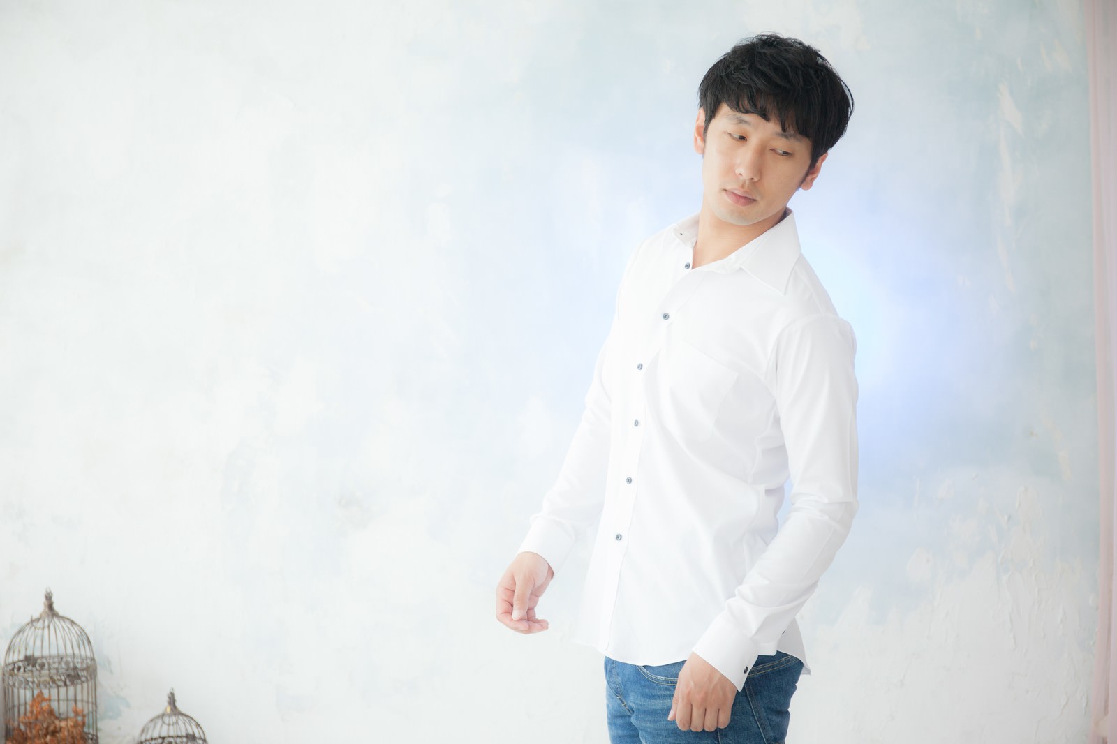 白いシャツを着た男性が頭に手を当てて下を向いている［モデル：大川竜弥］