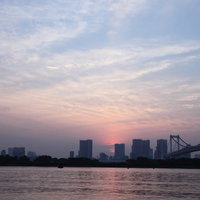夕焼けに染まる東京お台場のレインボーブリッジと都市風景の写真