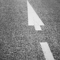 アスファルトの道路に描かれた白い三角の矢印と長方形のマーキングの写真