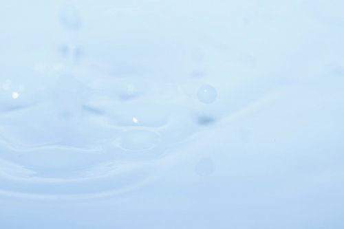 小さな泡や水滴が浮かぶ明るい水面の波紋を真上から撮影した写真