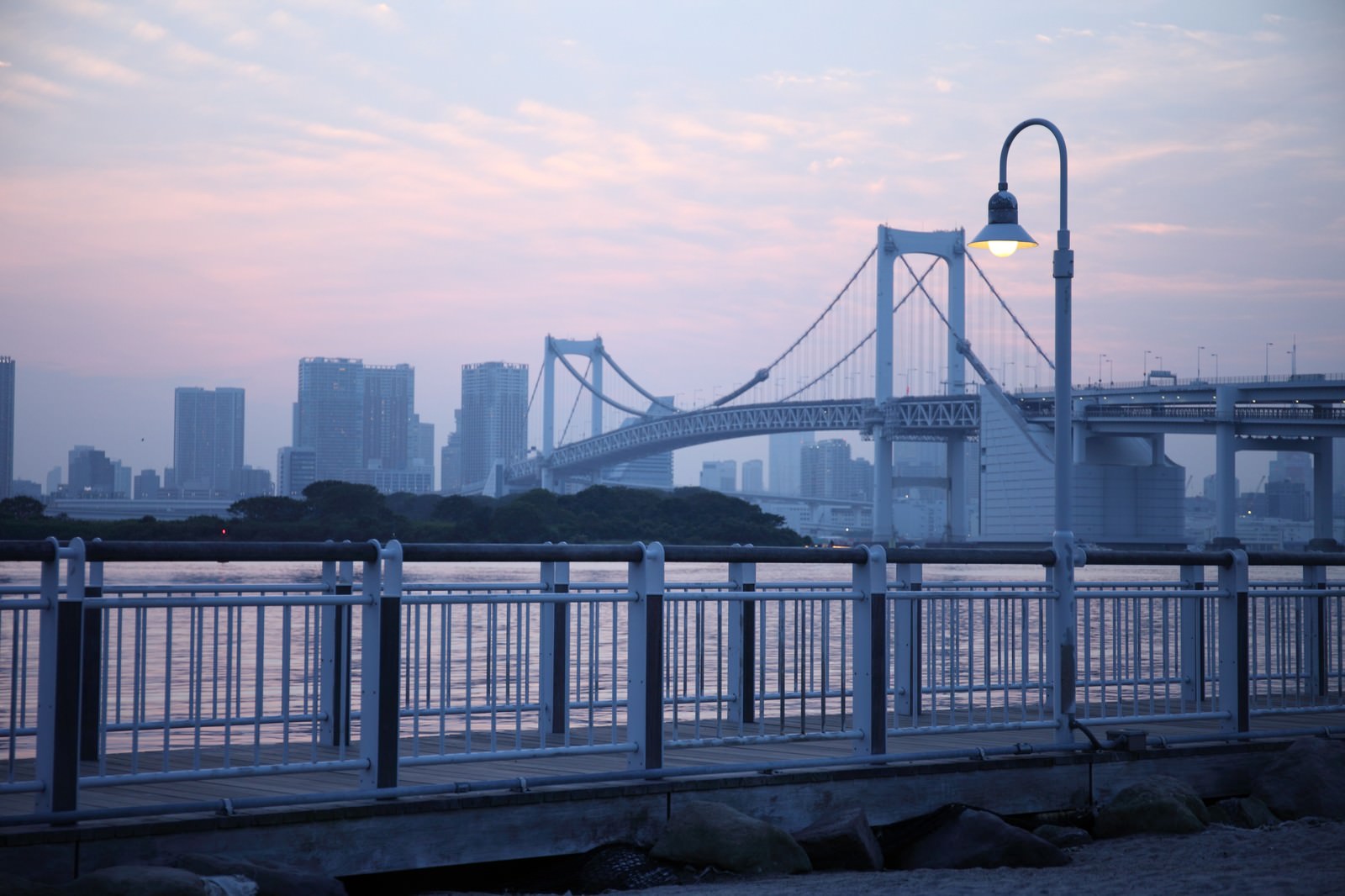 夕暮れの港湾エリアに柵越しに見えるレインボーブリッジと高層ビル