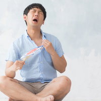 エアコン無しで夏を乗り切る男性、うちわで仰ぎ汗をぬぐうの写真