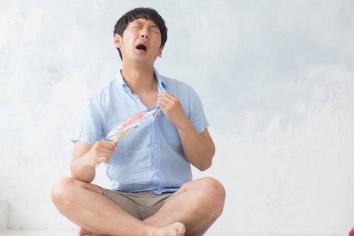 エアコン無しで夏を乗り切る男性、うちわで仰ぎ汗をぬぐう