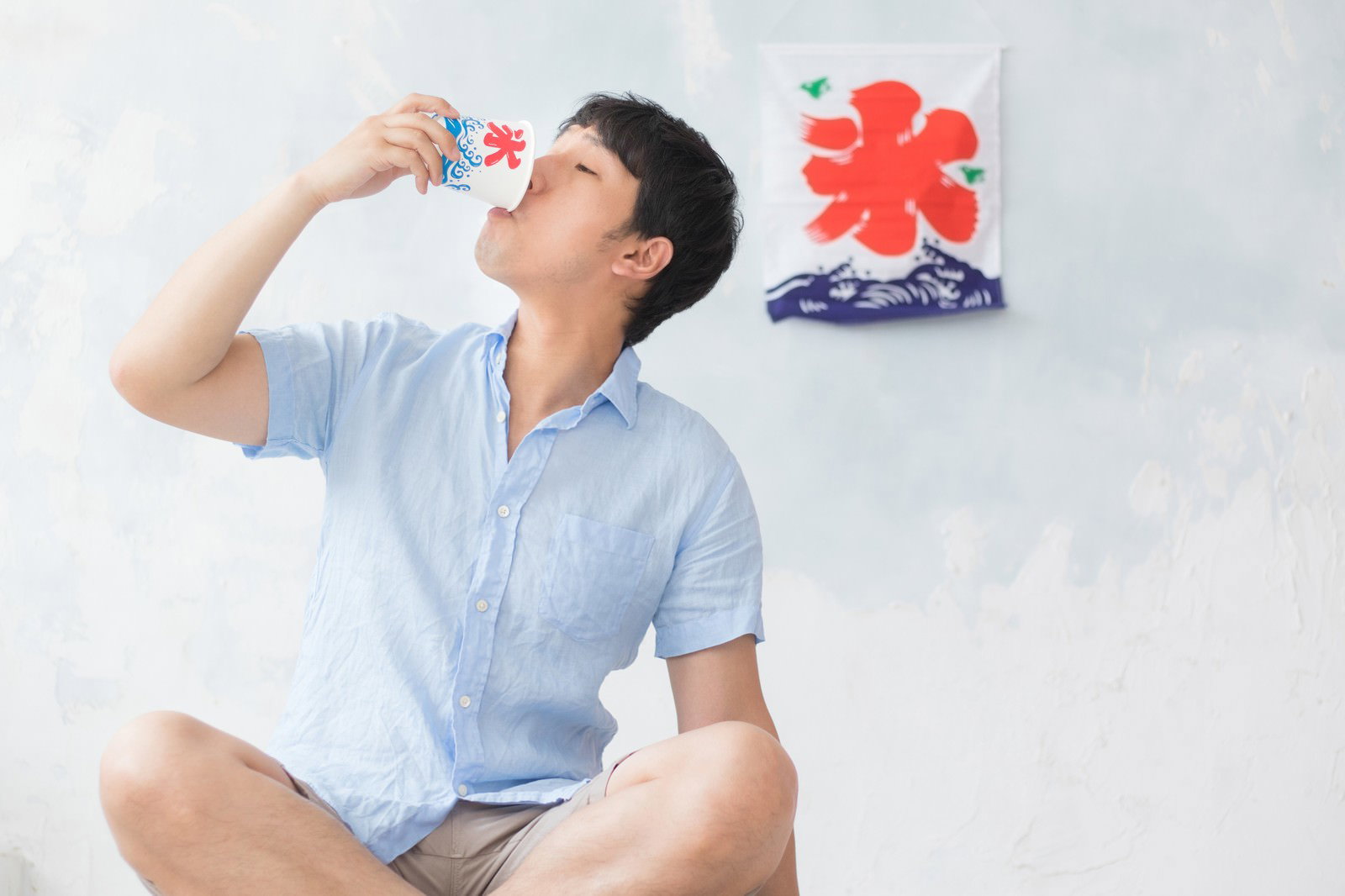 かき氷を飲み干す水色のシャツを着た男性が上を向いている［モデル：大川竜弥］