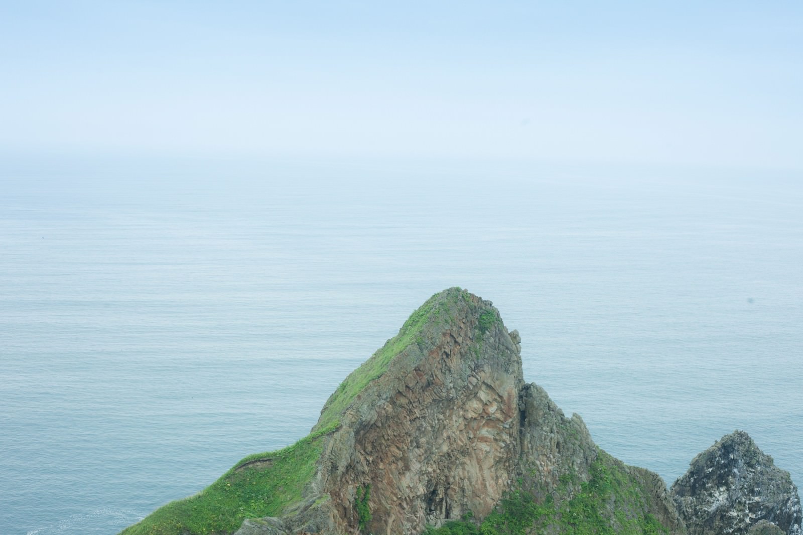 苔むした岩礁が浮かぶ穏やかな海
