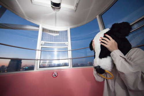 高層ビルの展望室で頭を抱える牛のかぶりものをした女性