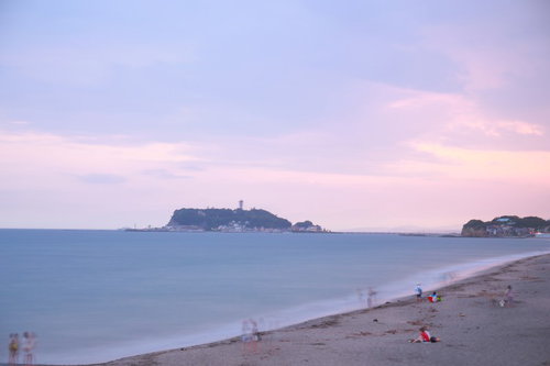 夕暮れの江ノ島と波打ち際で遊ぶ人々、砂浜の海岸風景