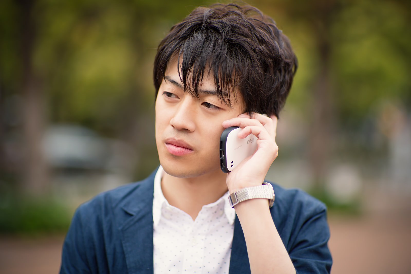 屋外でスマートフォンを持ち別れ話を聞く男性［モデル：Tsuyoshi.］