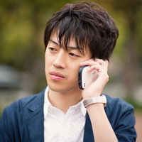 屋外で電話をかけるスーツ姿の男性の写真