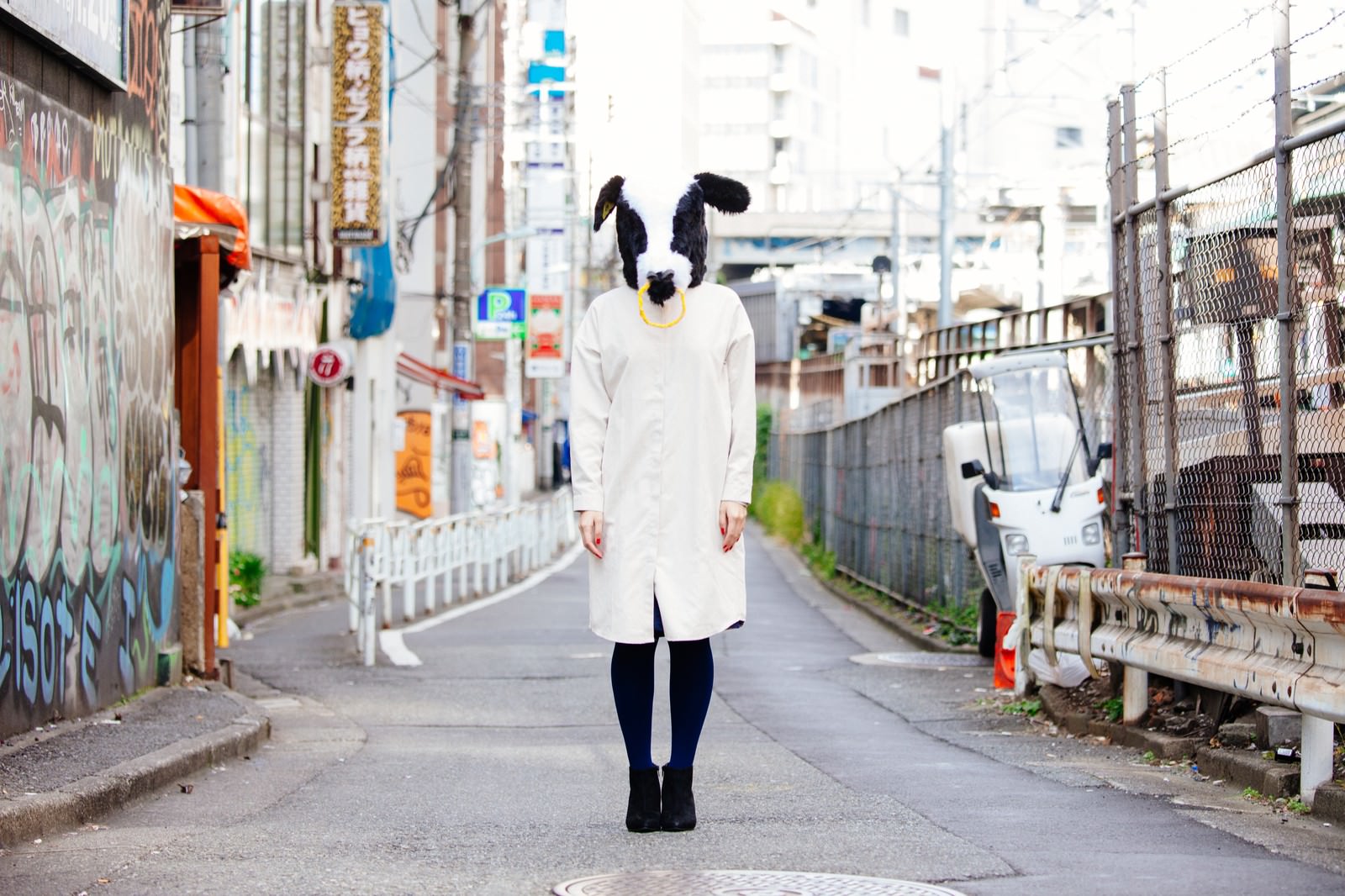 冬の交差点で手を振りながら横断歩道を渡る女性［モデル：古性のっち］