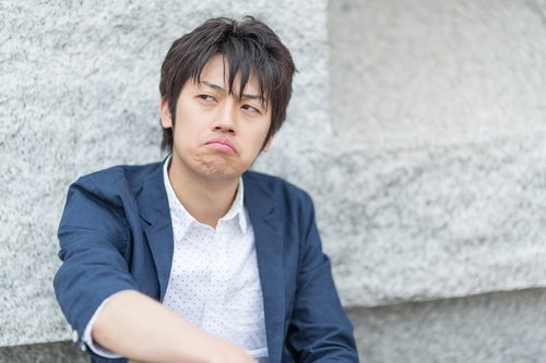 口をへの字に曲げて不満そうな表情のWebデザイナー